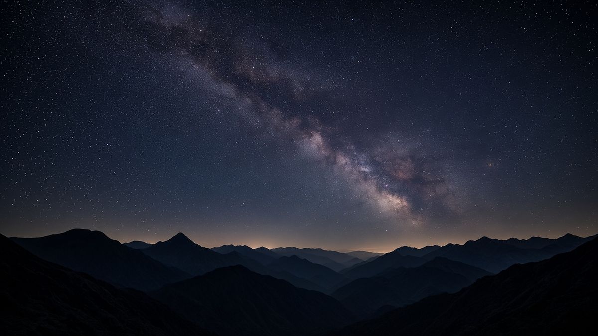 Milky Way galaxy arching over dark mountain silhouettes